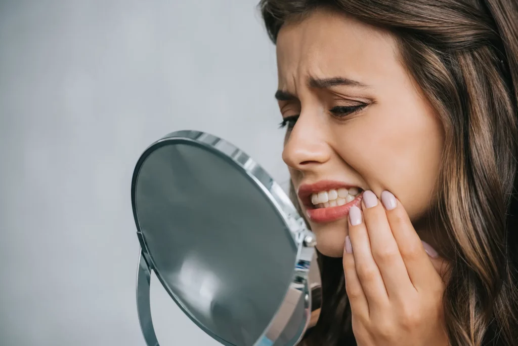 woman looking at teeth in the mirror